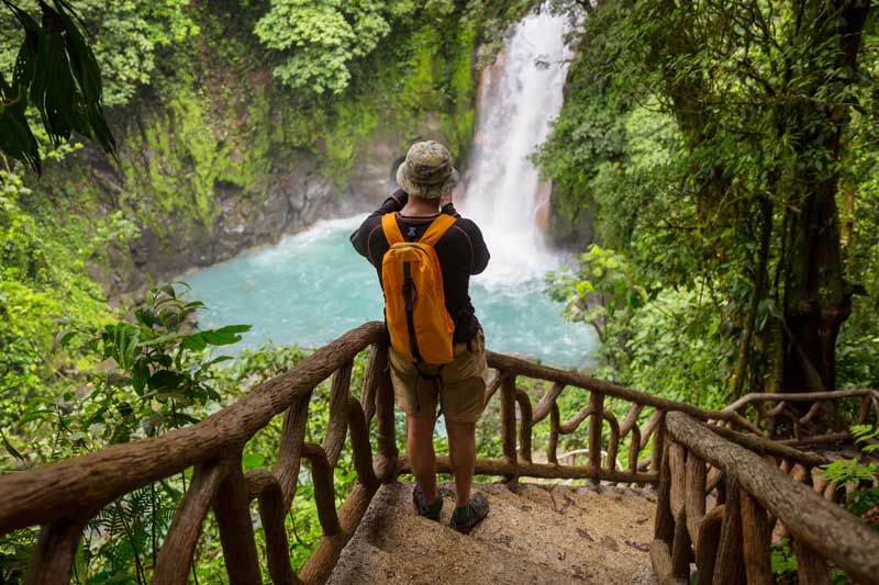 A man looking at a waterfall in the jungle.